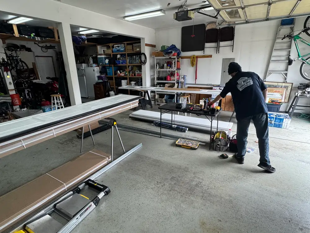 Still Movin Garage Door technician laying out new door sections, track and hardware inside a garage