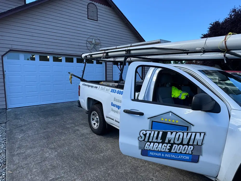 Still Movin Garage Door service truck parked on a driveway beside a newly installed white garage door